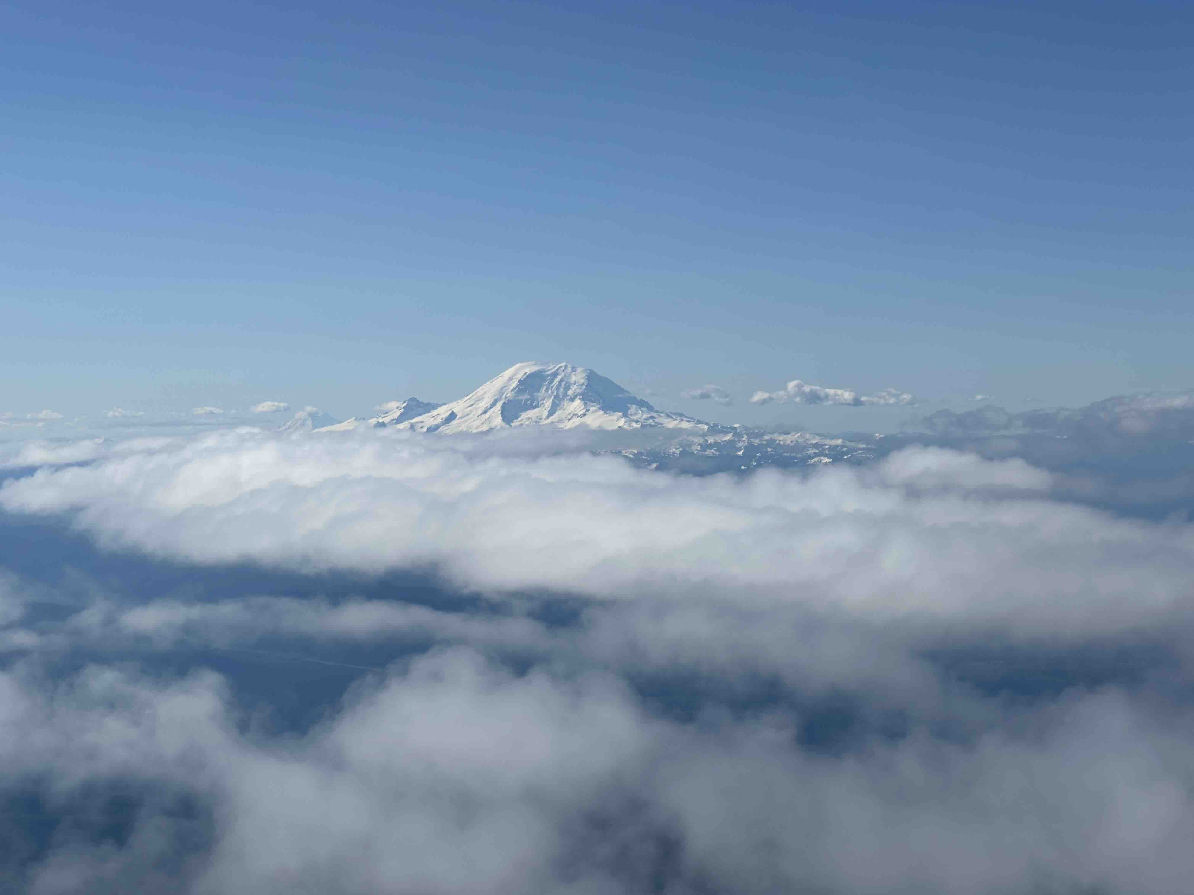 飛行機から見た雲の上にそびえるシアトルのマウントレーニア。写真: Adriana Villela